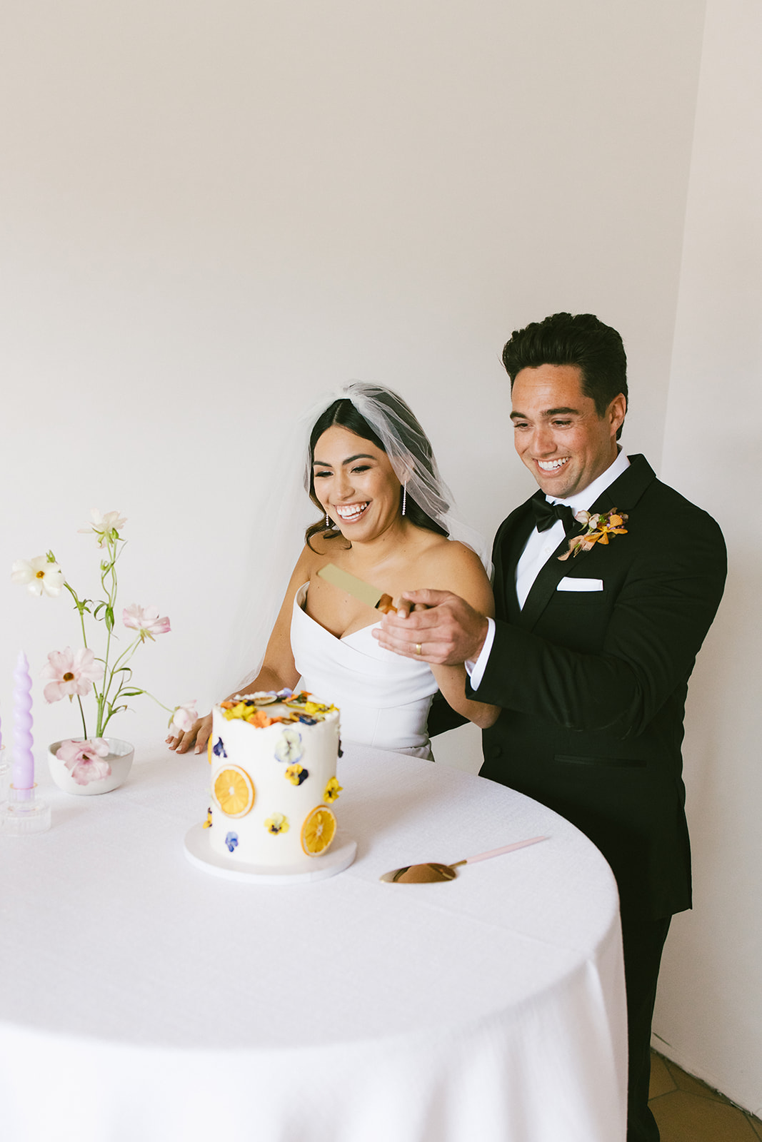 bride and groom smiling as they cut their cake 