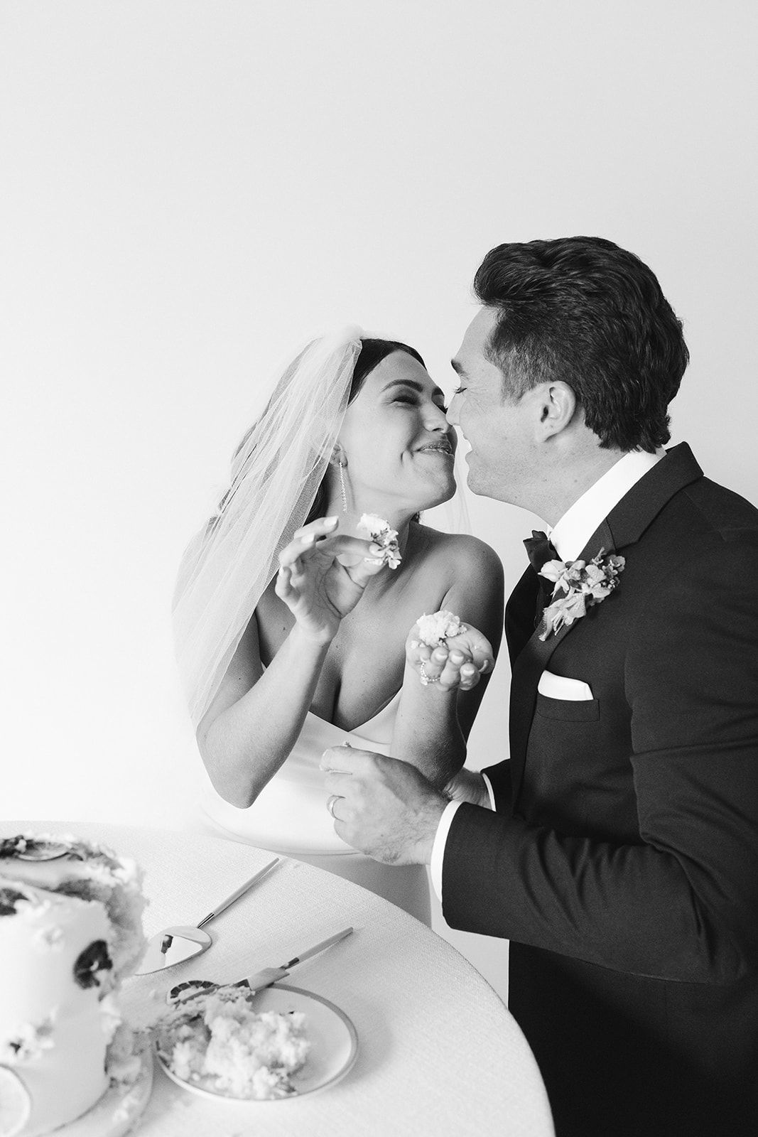 bride and groom eating their wedding cake and smiling 