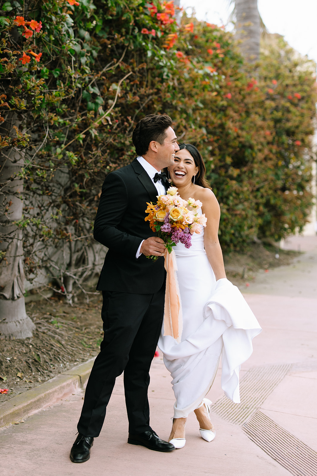 bride and groom smiling on the side of the street 