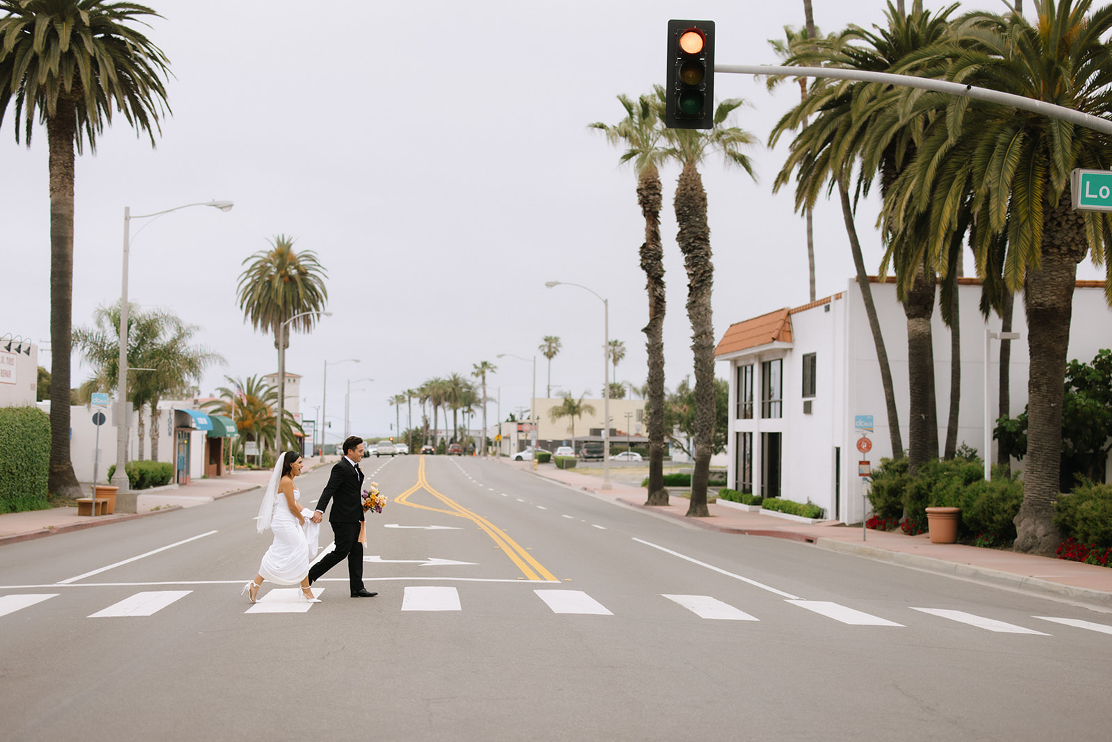 bride and groom walking down the street to the beach 