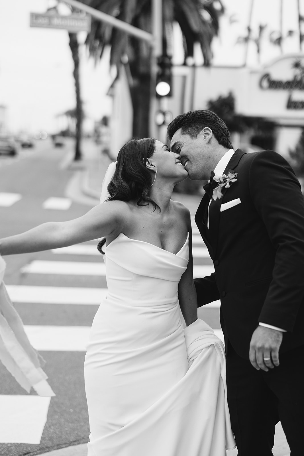 bride and groom kissing as they walk down the street 