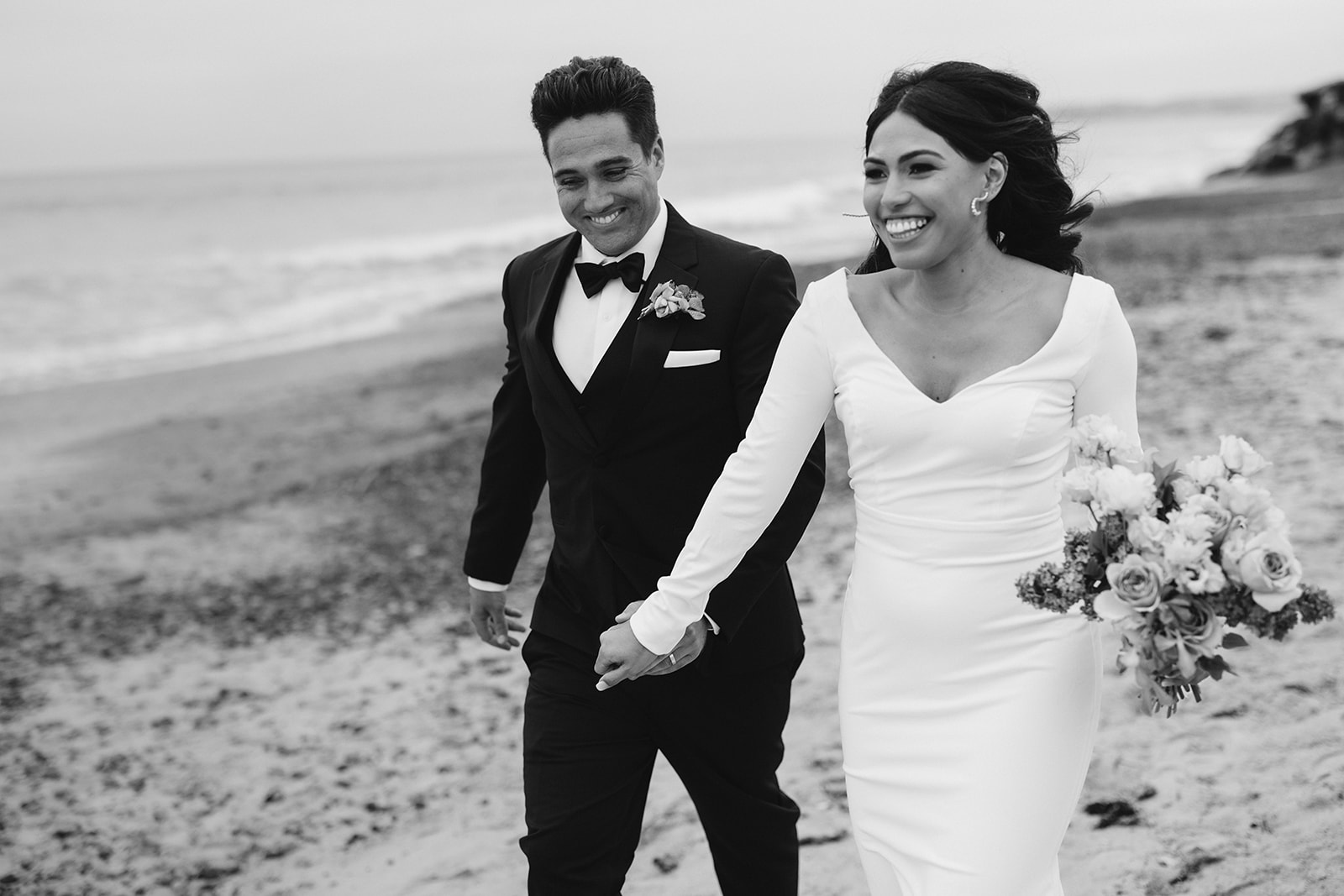 bride and groom running together on the beach 