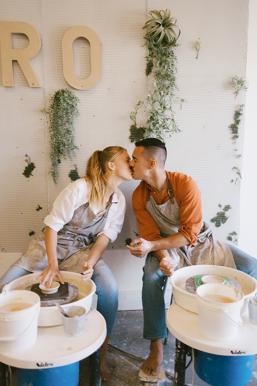 a couple kissing while making pottery during a date night photoshoot 