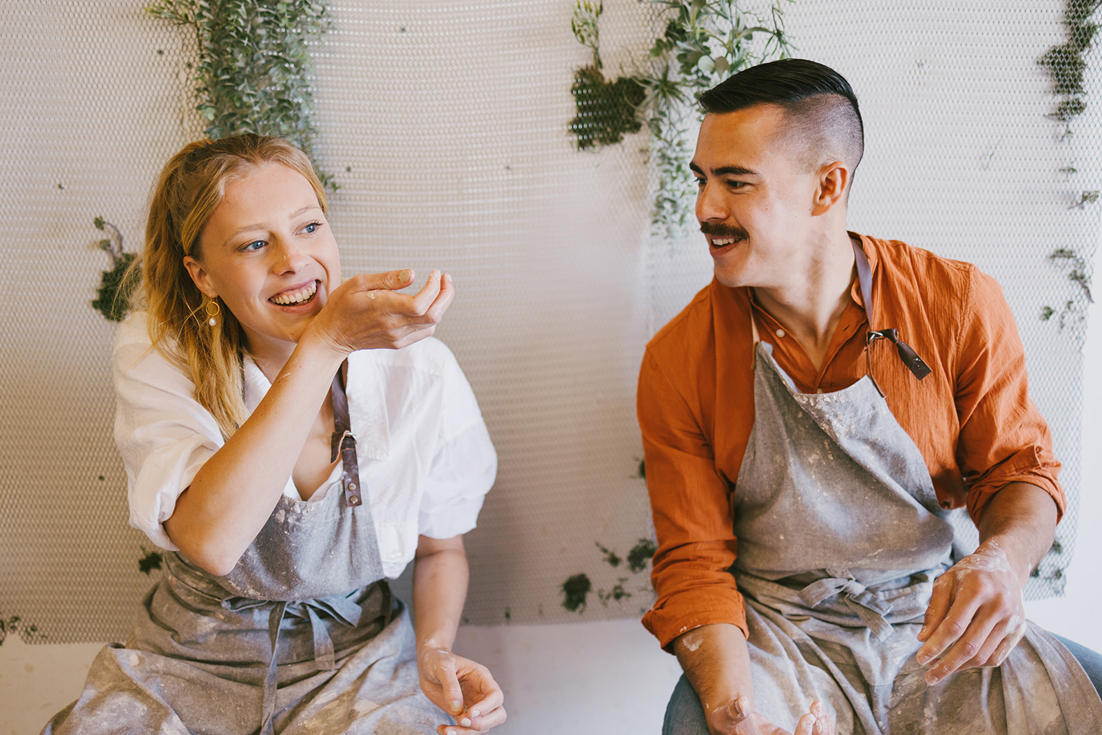 a couple already getting messy while making pottery together for date night 