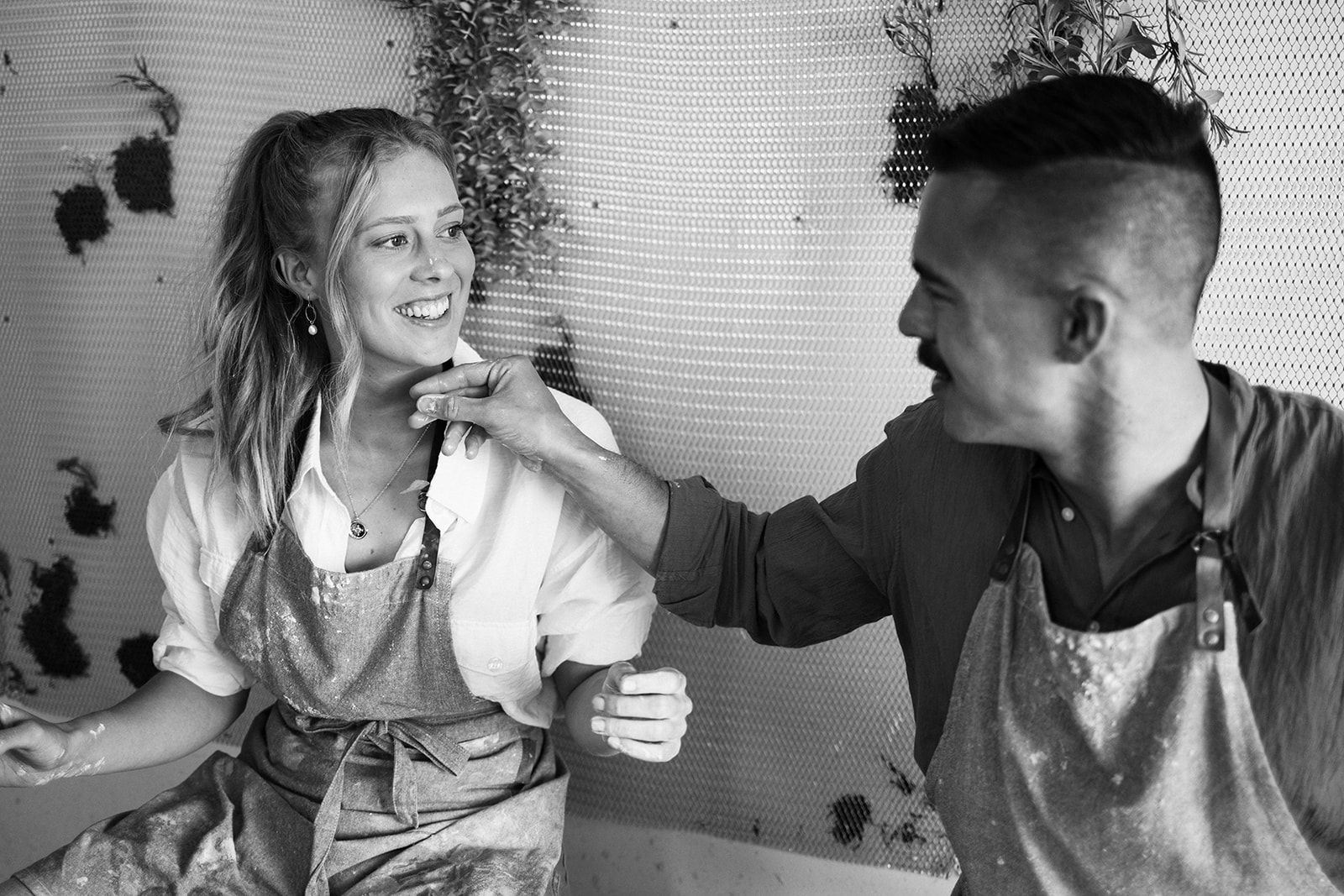 a couple smiling at each other as they make their pots