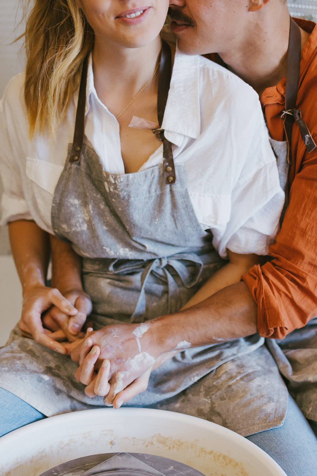 a couple holding each other as they make pottery during a date night photoshoot 