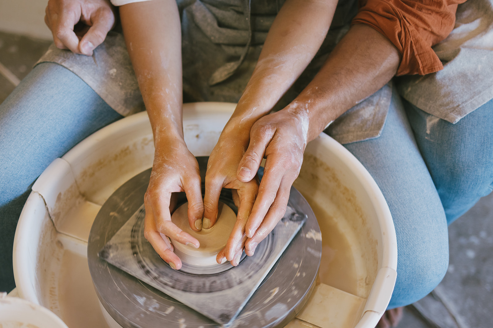 a couple making pottery together at the wheel 