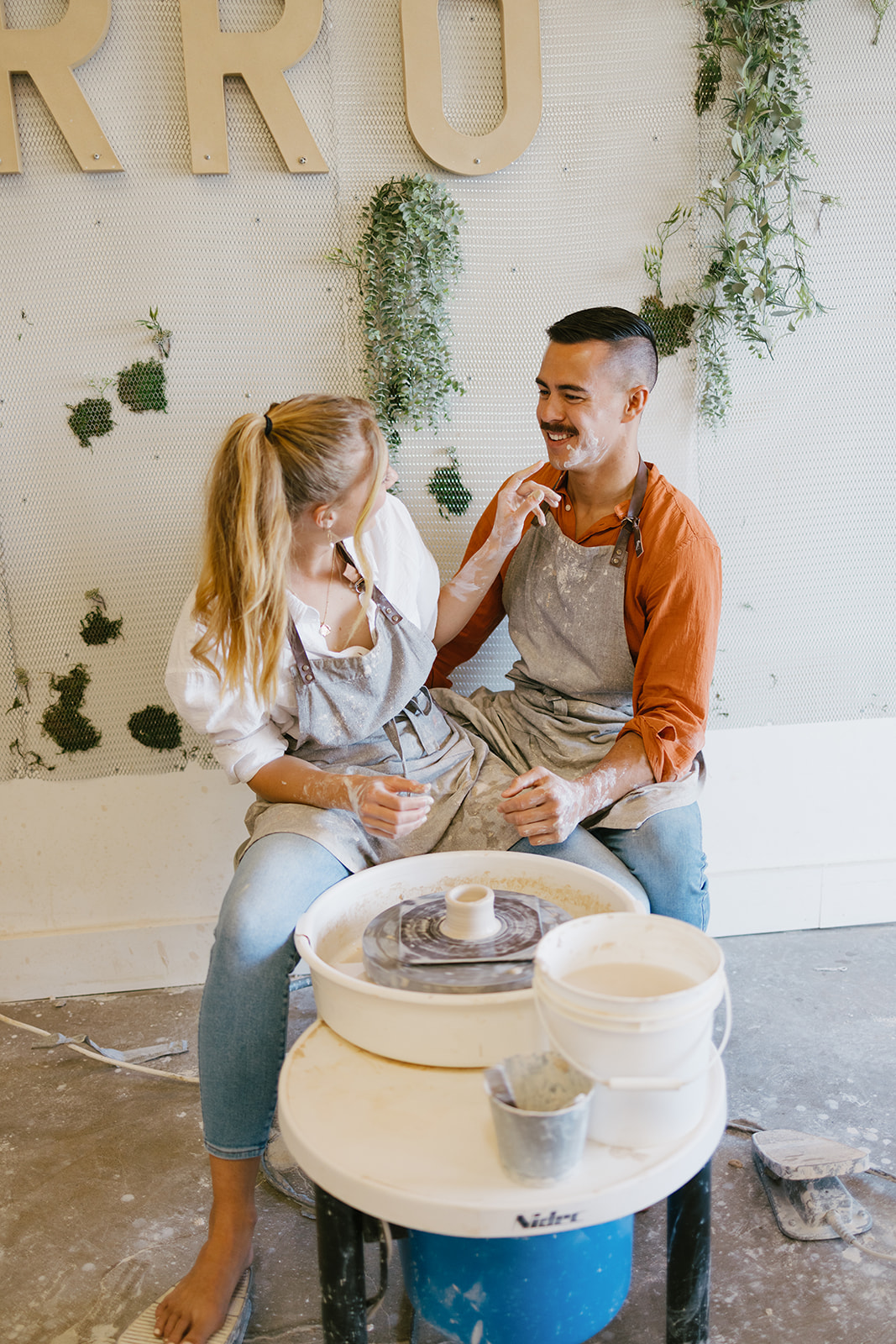 a couple getting messy wile making pottery during a date night photoshoot 