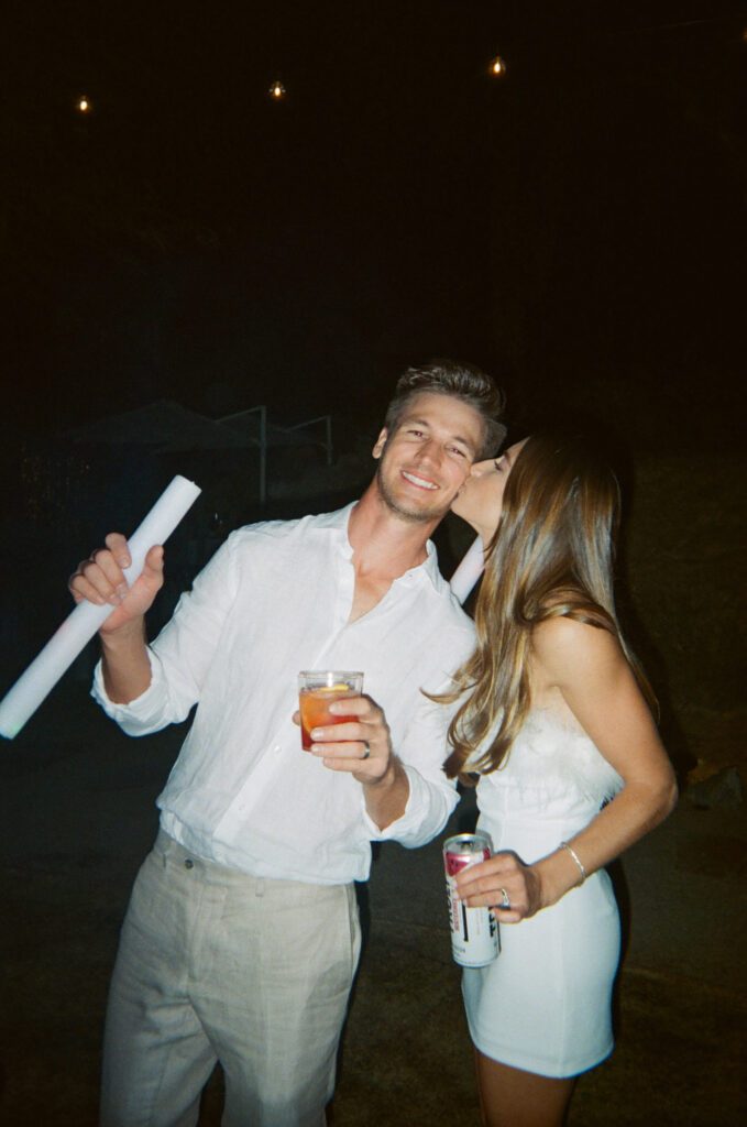 bride kissing groom on the check at Palm Springs wedding reception