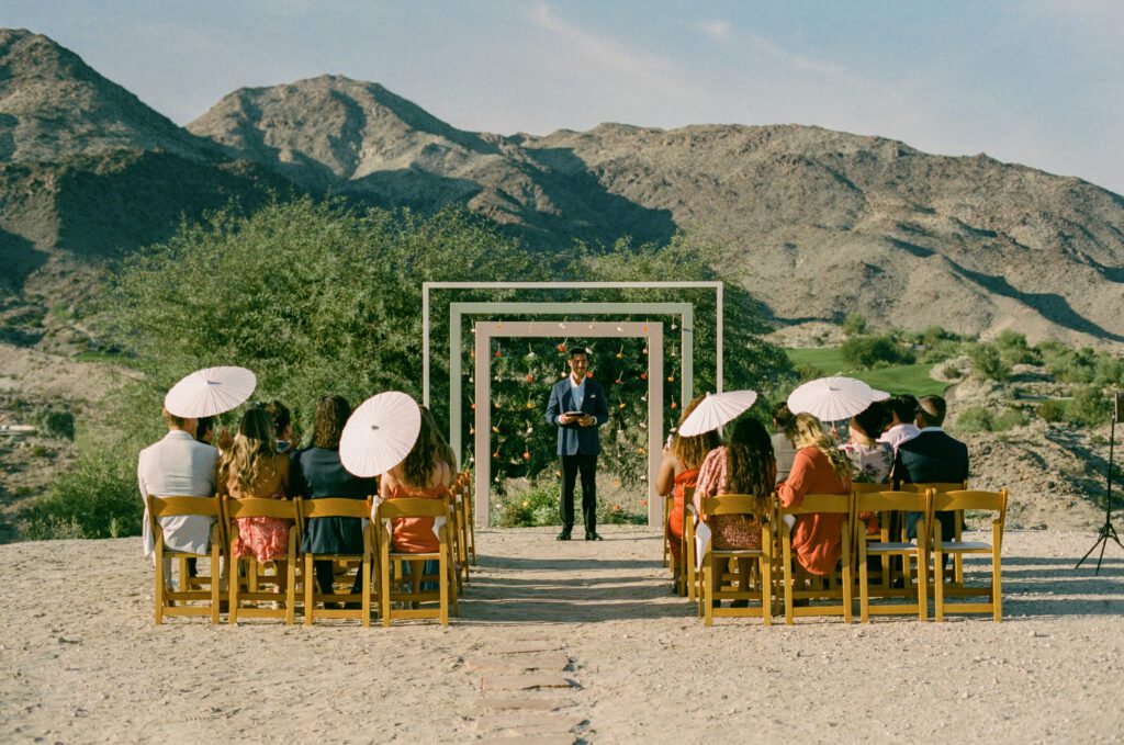 wedding guests with their umbrellas sitting at the Palm Springs wedding ceremony