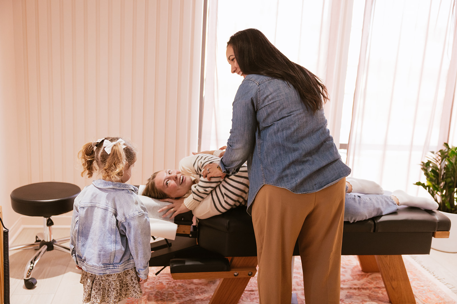 lifestyle branding photography for a Chiropractor as she works on a patient and they all are laughing