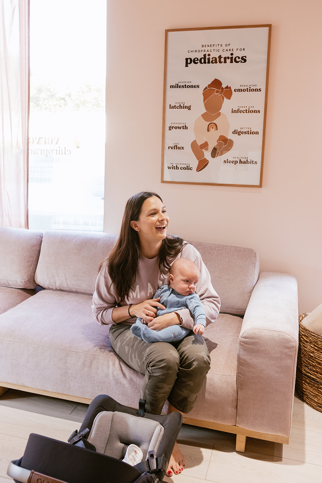 lifestyle branding photography for a Chiropractor as a patient is laughing while holding her baby