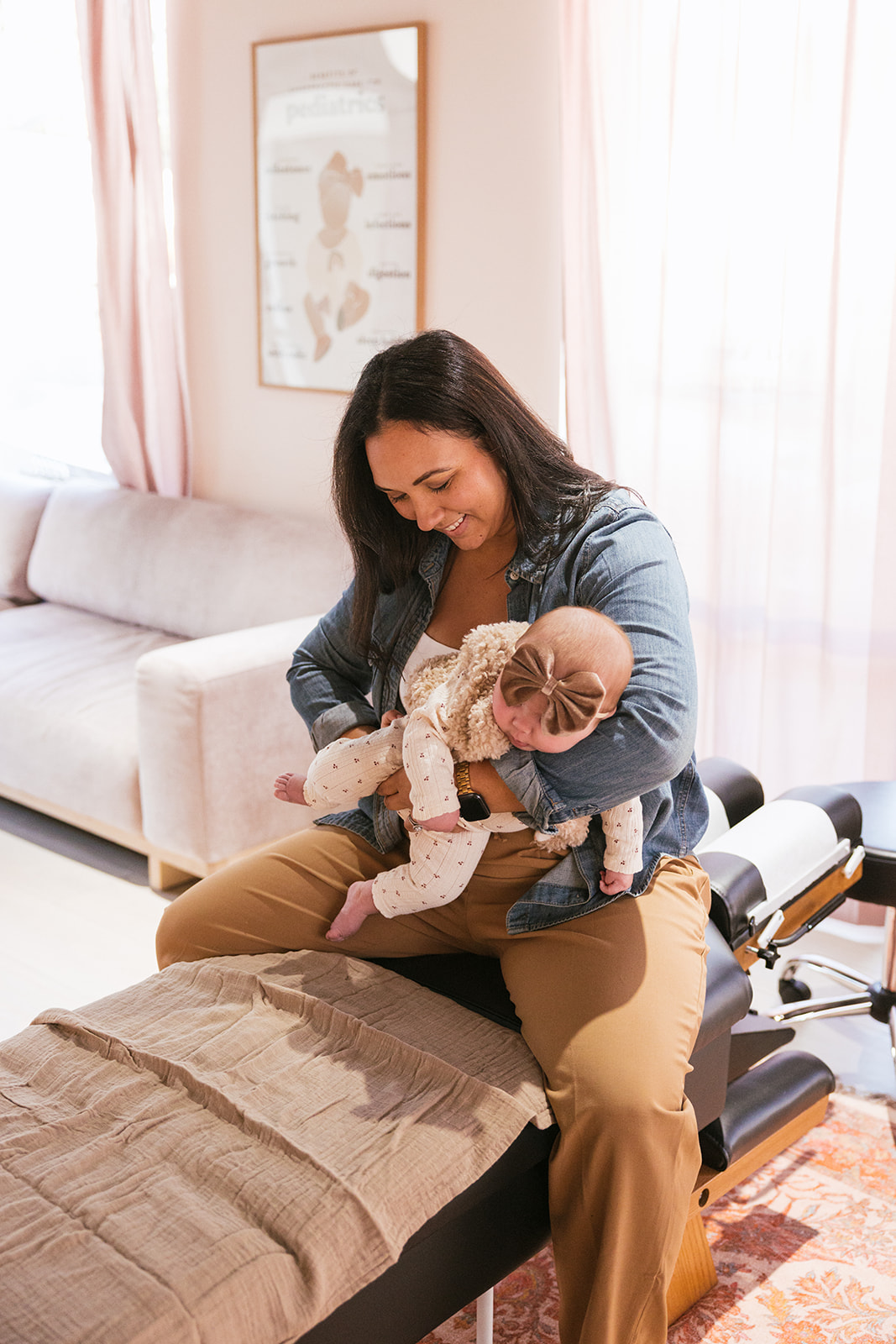 the chiropractor holding a baby as she works on her