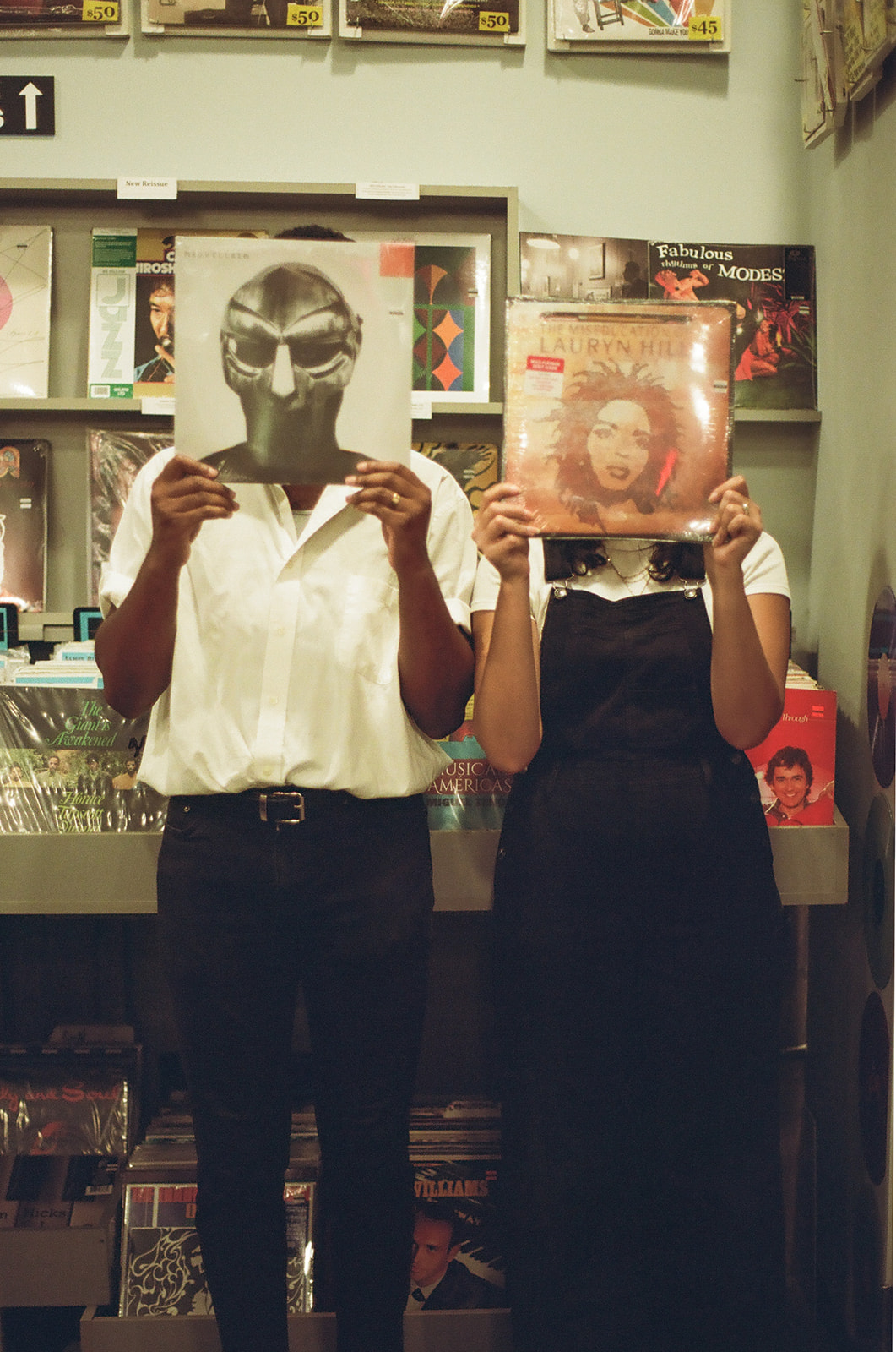 a couple holding up records to their face during their fun couples photoshoot shot on film