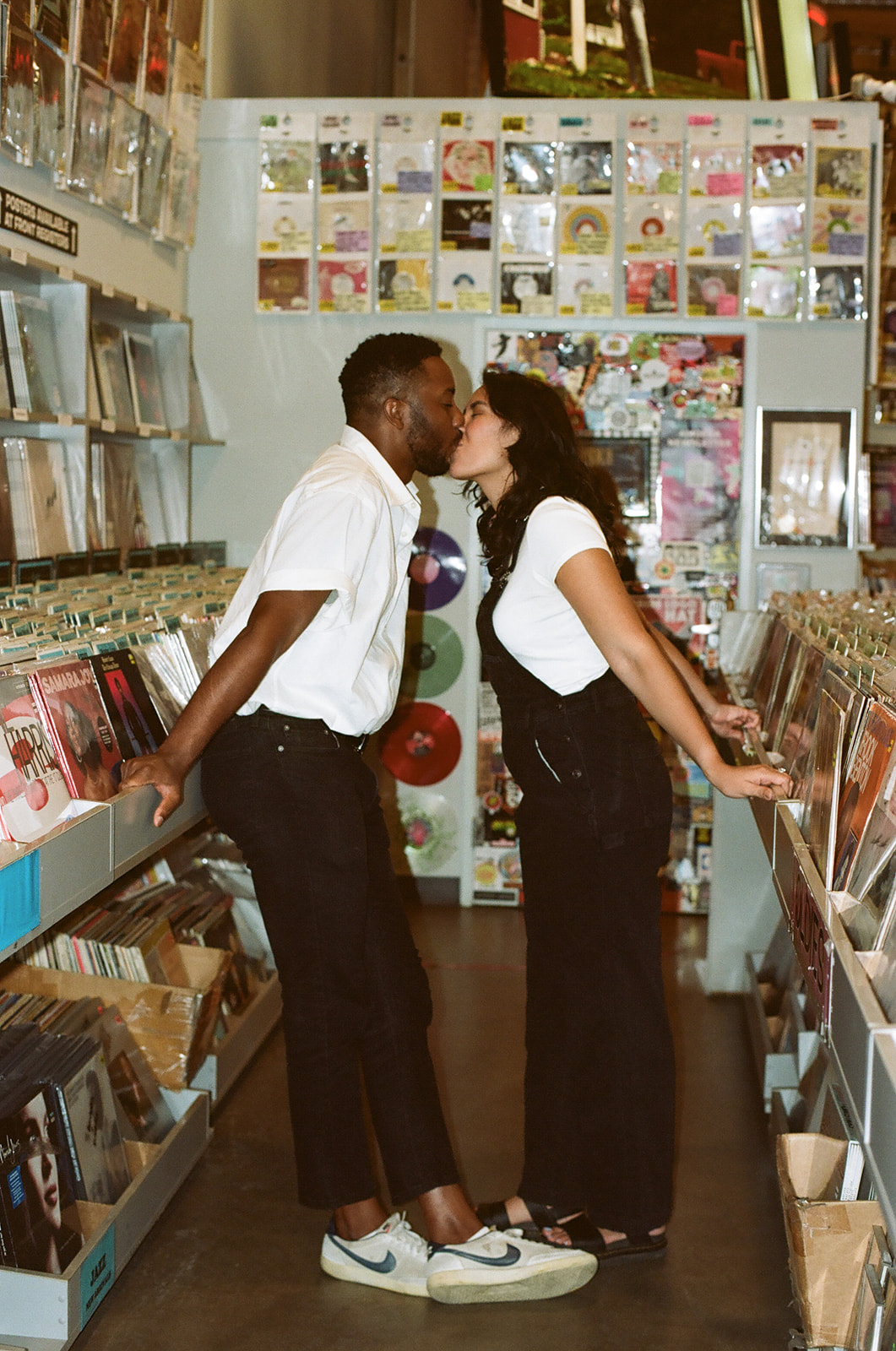 a couple kissing in the aisle of the record store shot on film
