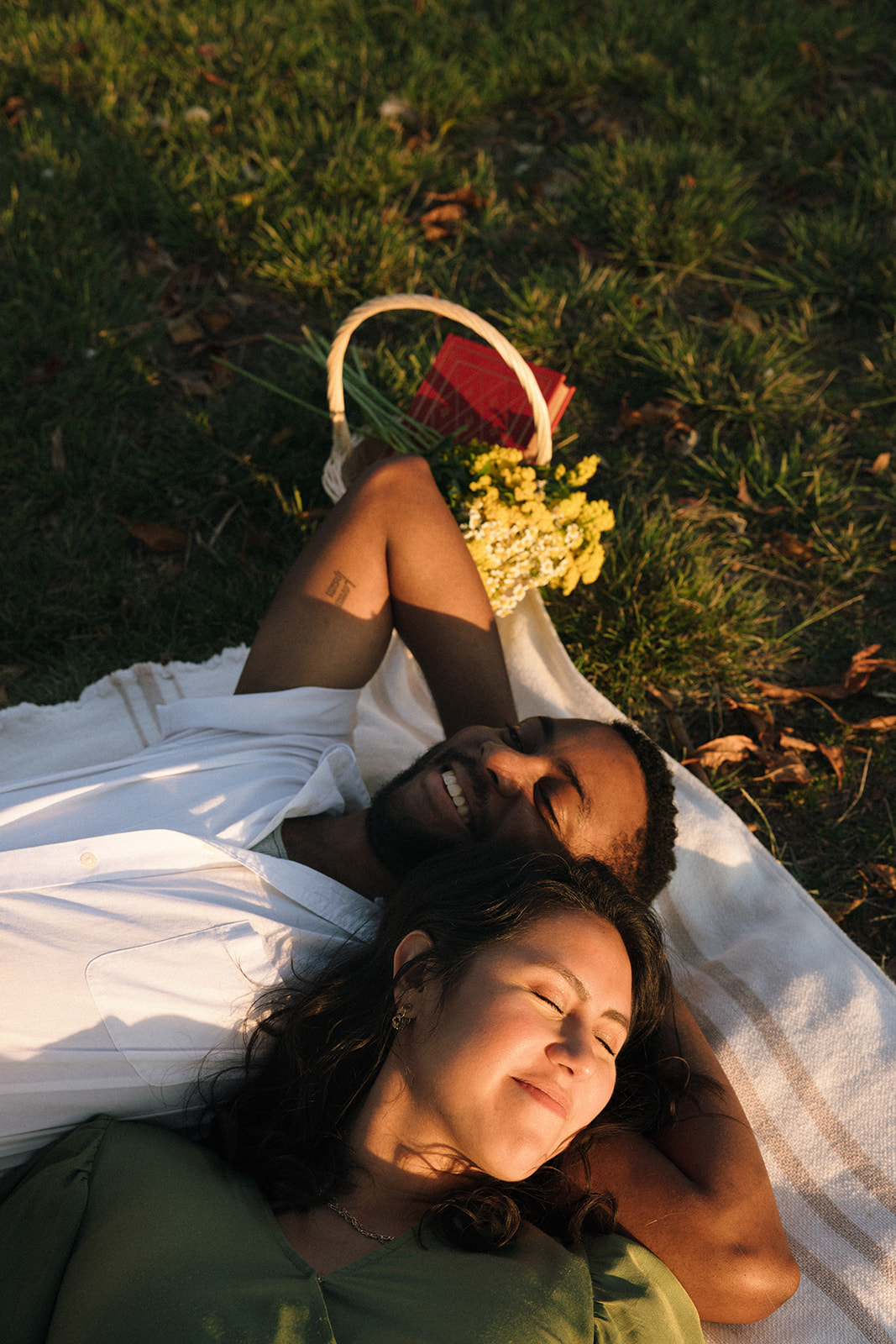 a couple laying together on a blanket in the sun during their fun couples photoshoot
