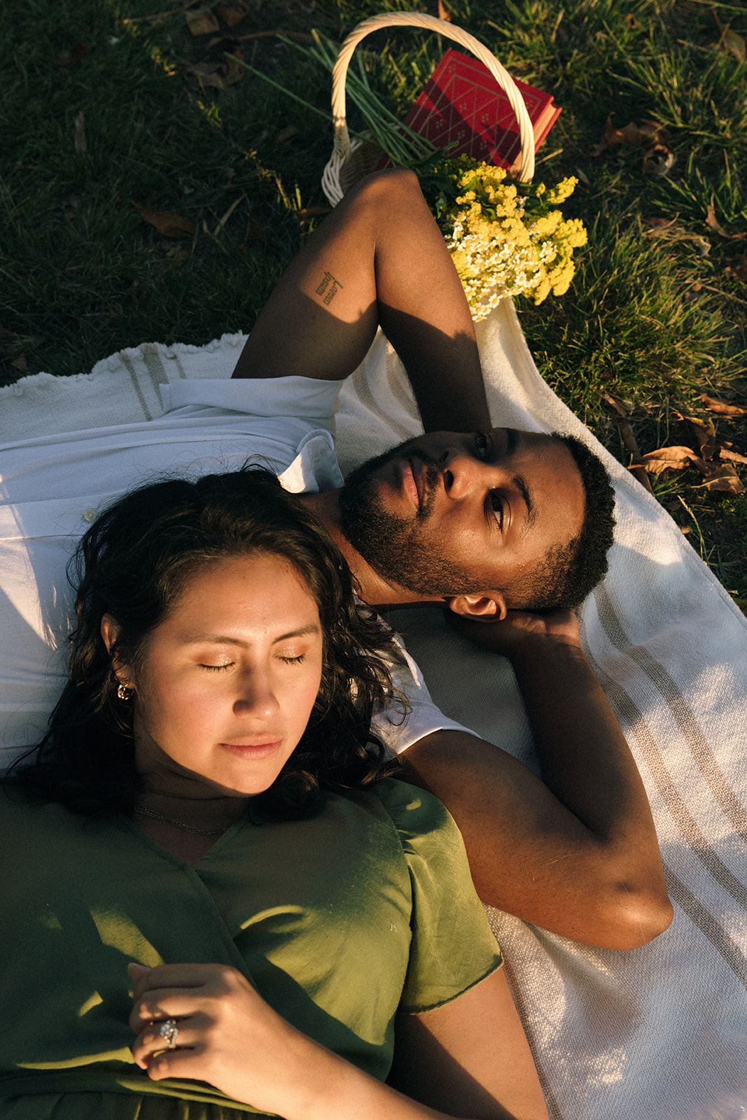 a couple laying on a blanket together during a picnic at the park