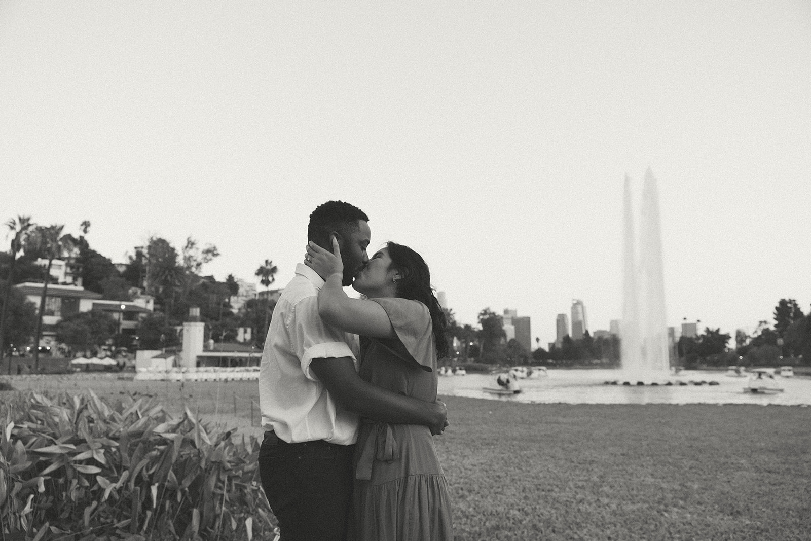 a couple kissing in front of a fountain at the park 