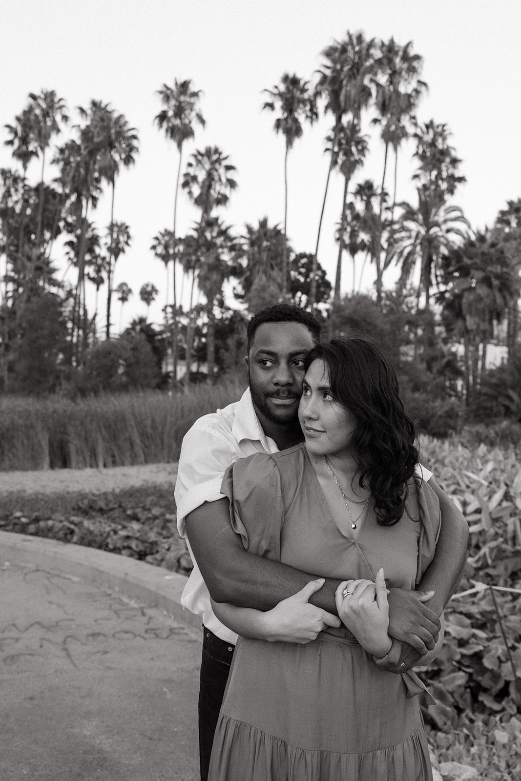 a man hugging a woman from behind in the park during their fun couples photoshoot