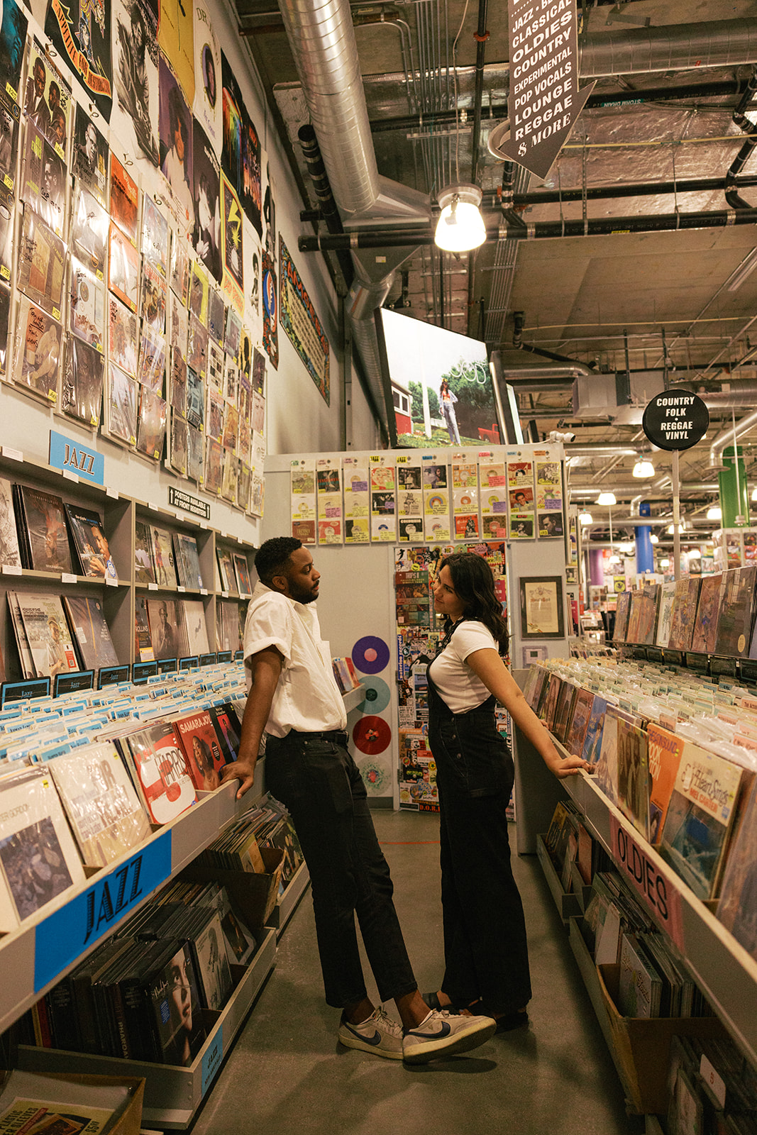 a couple standing in the aisle of a record store 