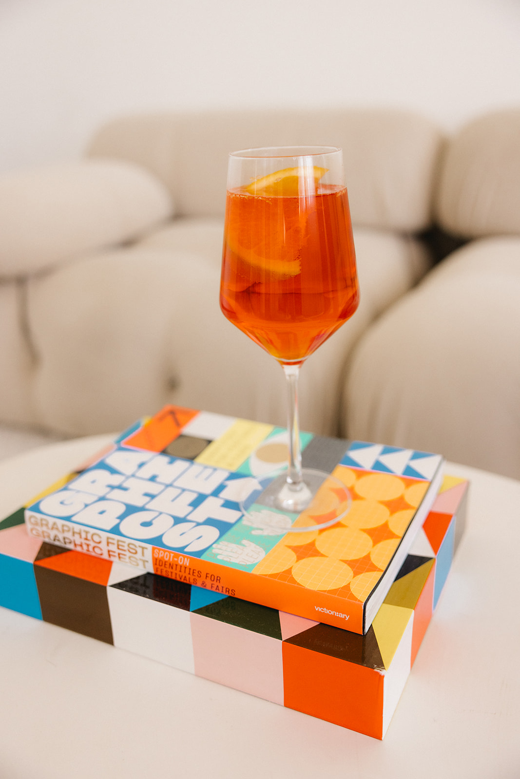 an aperol spritz on top of colorful coffee table books 