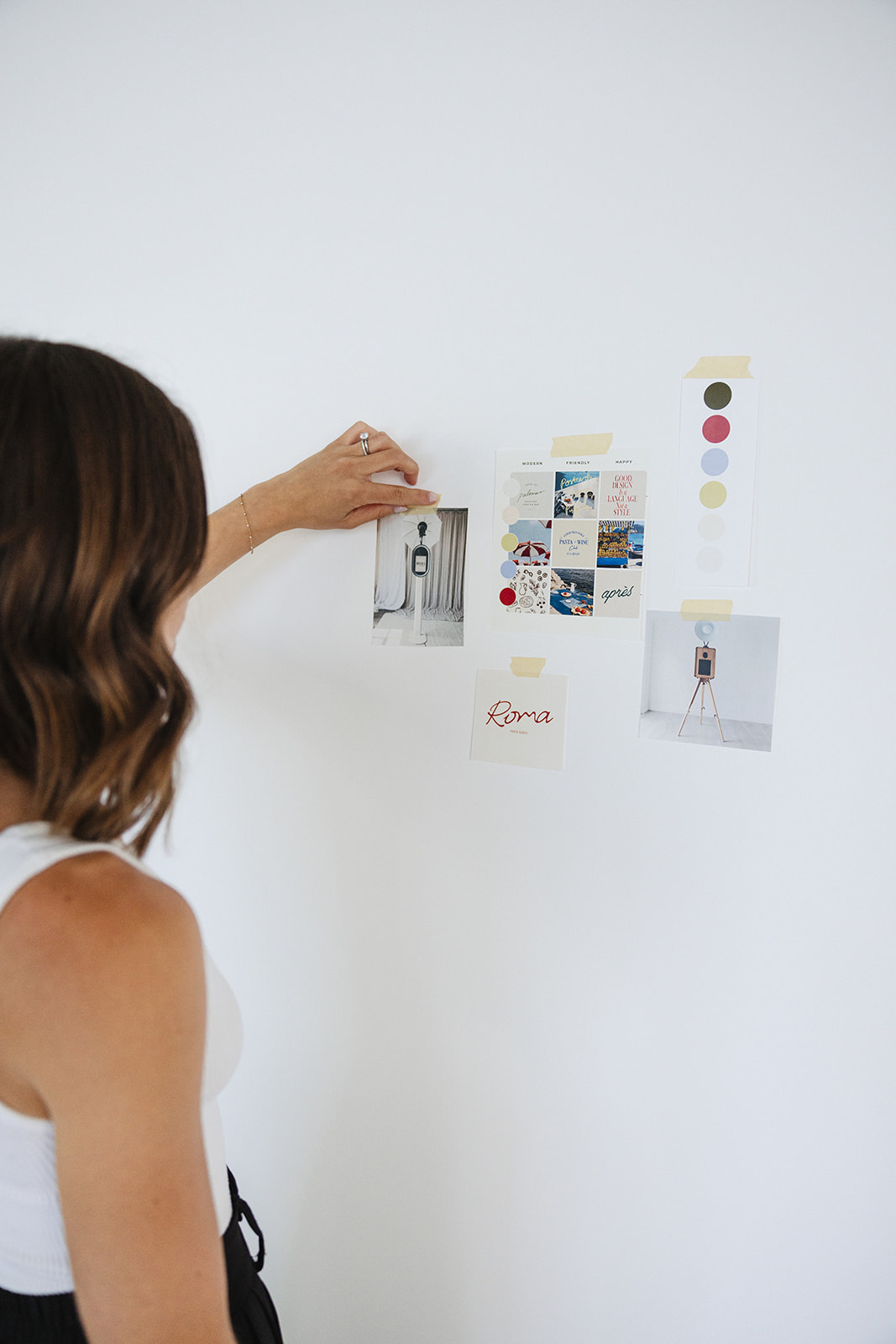 a woman putting up her branding materials on the studio wall 