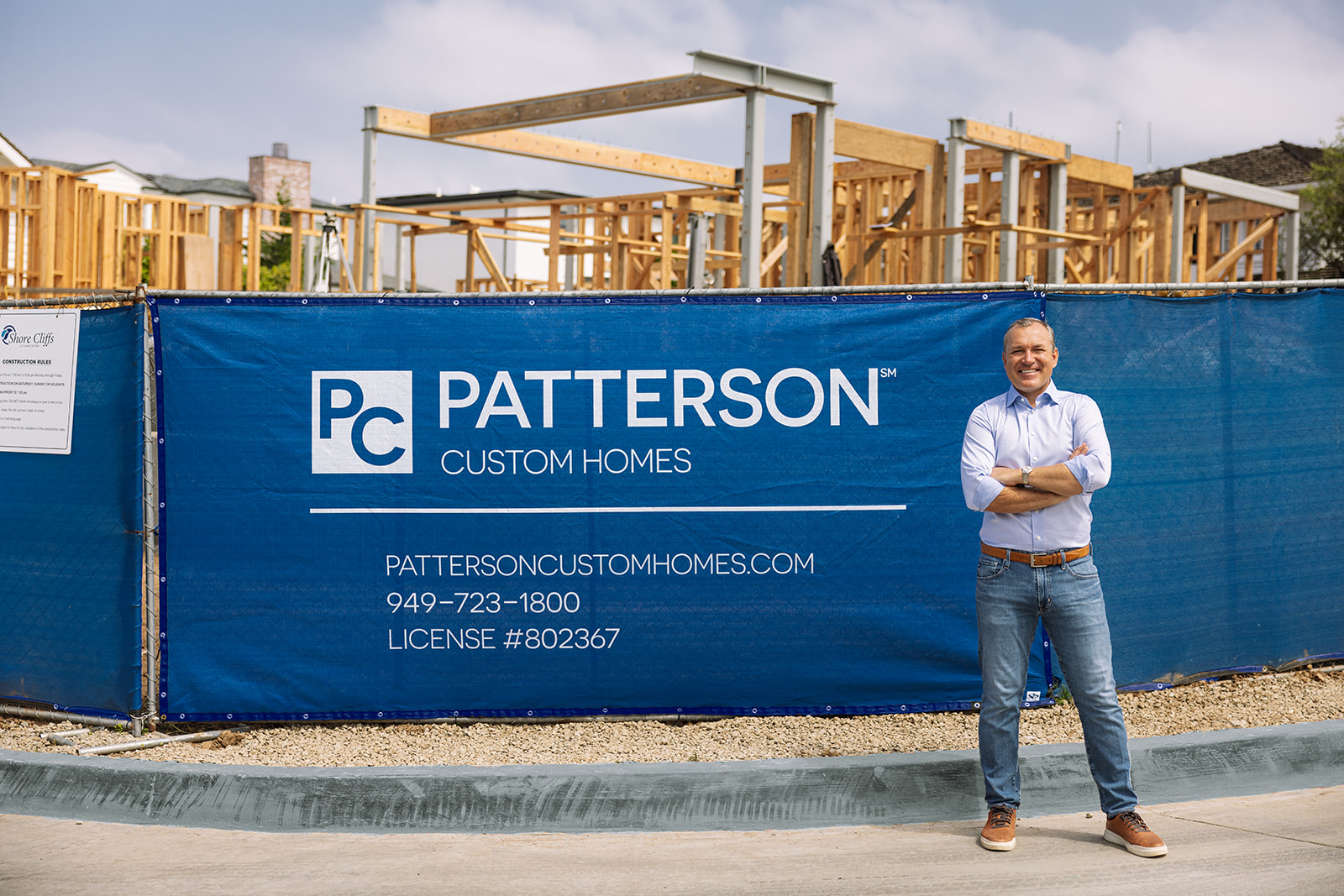 a man standing next to his business sign at a construction site for a brand photoshoot