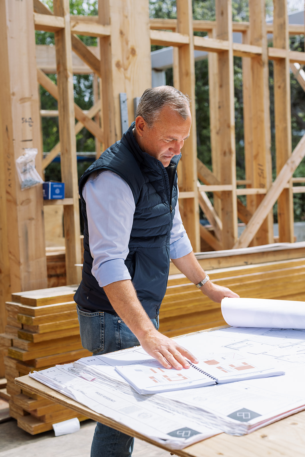a man standing in a house being framed looking over the plans during a brand photoshoot in SoCal 