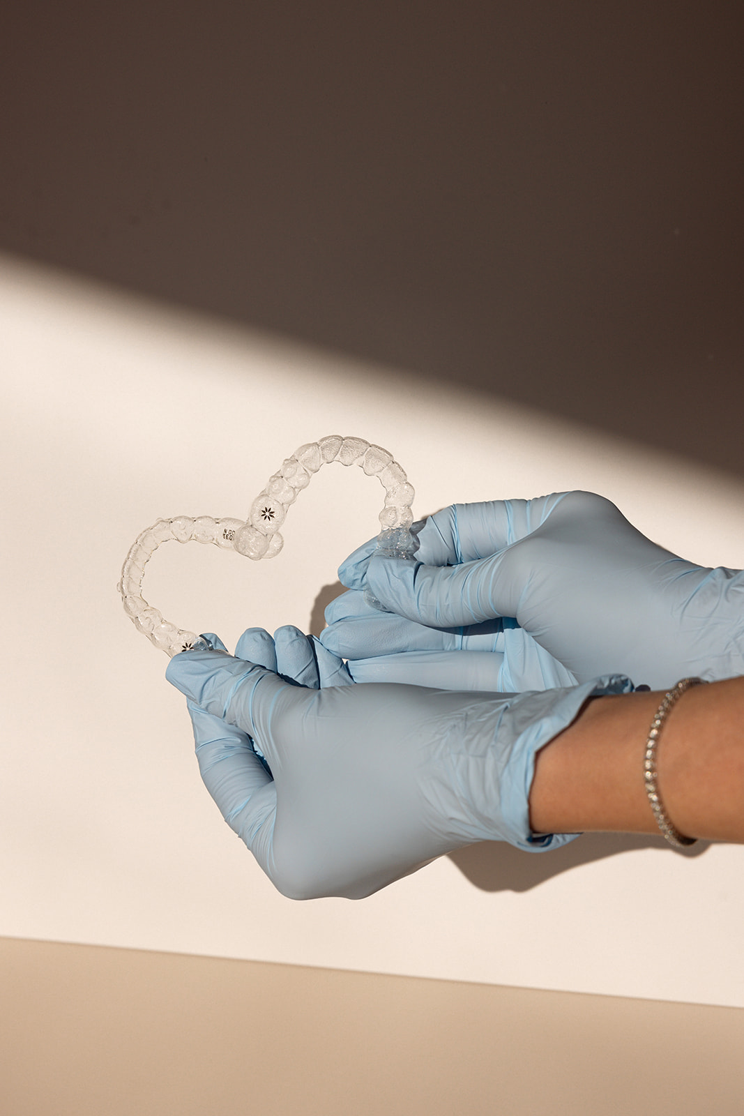 gloved hands holding up retainers to make a heart shape during a modern brand photoshoot 