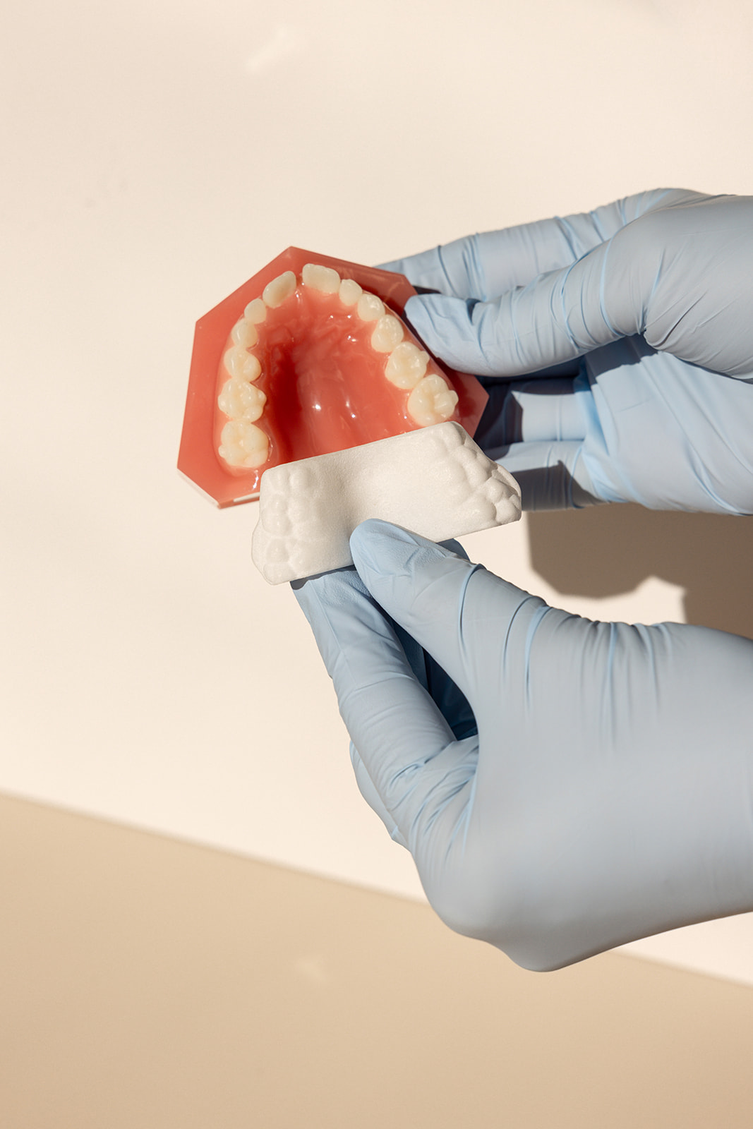 gloved hands holding a teeth model and a mold for branding photos in Orange County 