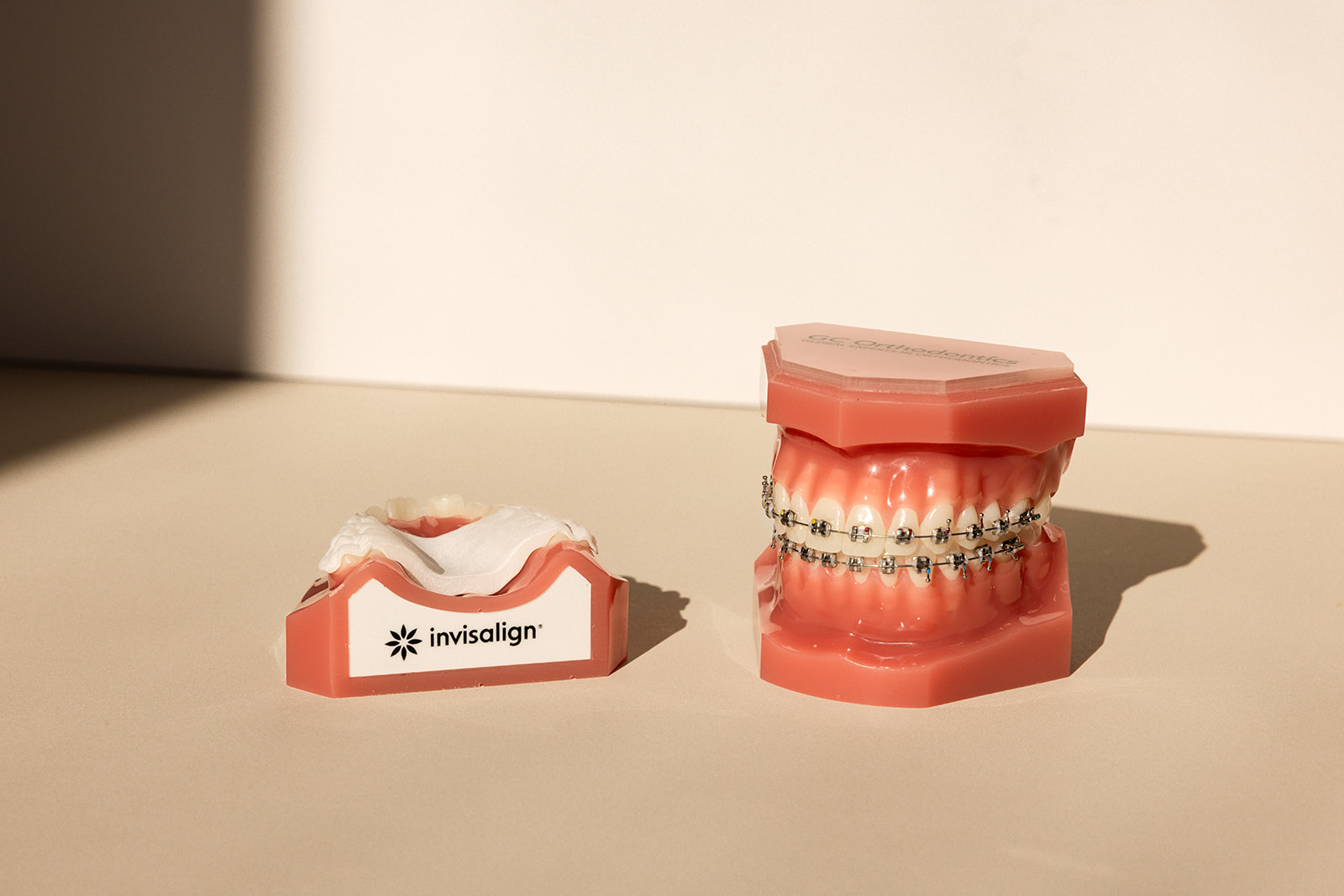 a model of teeth with braces next to invisalign molds 