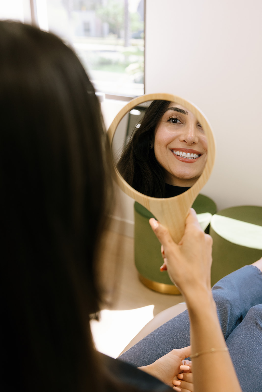 a woman smiling while looking into a mirror for business branding photos