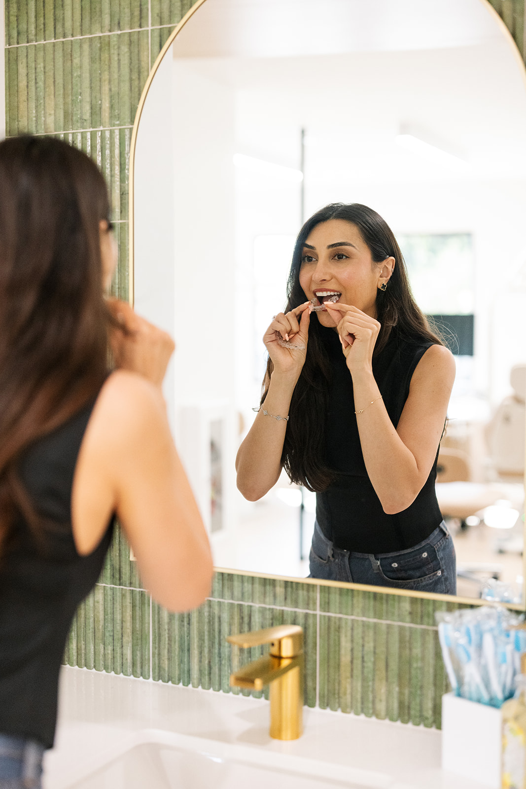 a woman flossing her teeth while looking in a mirror during a brand shoot in OC