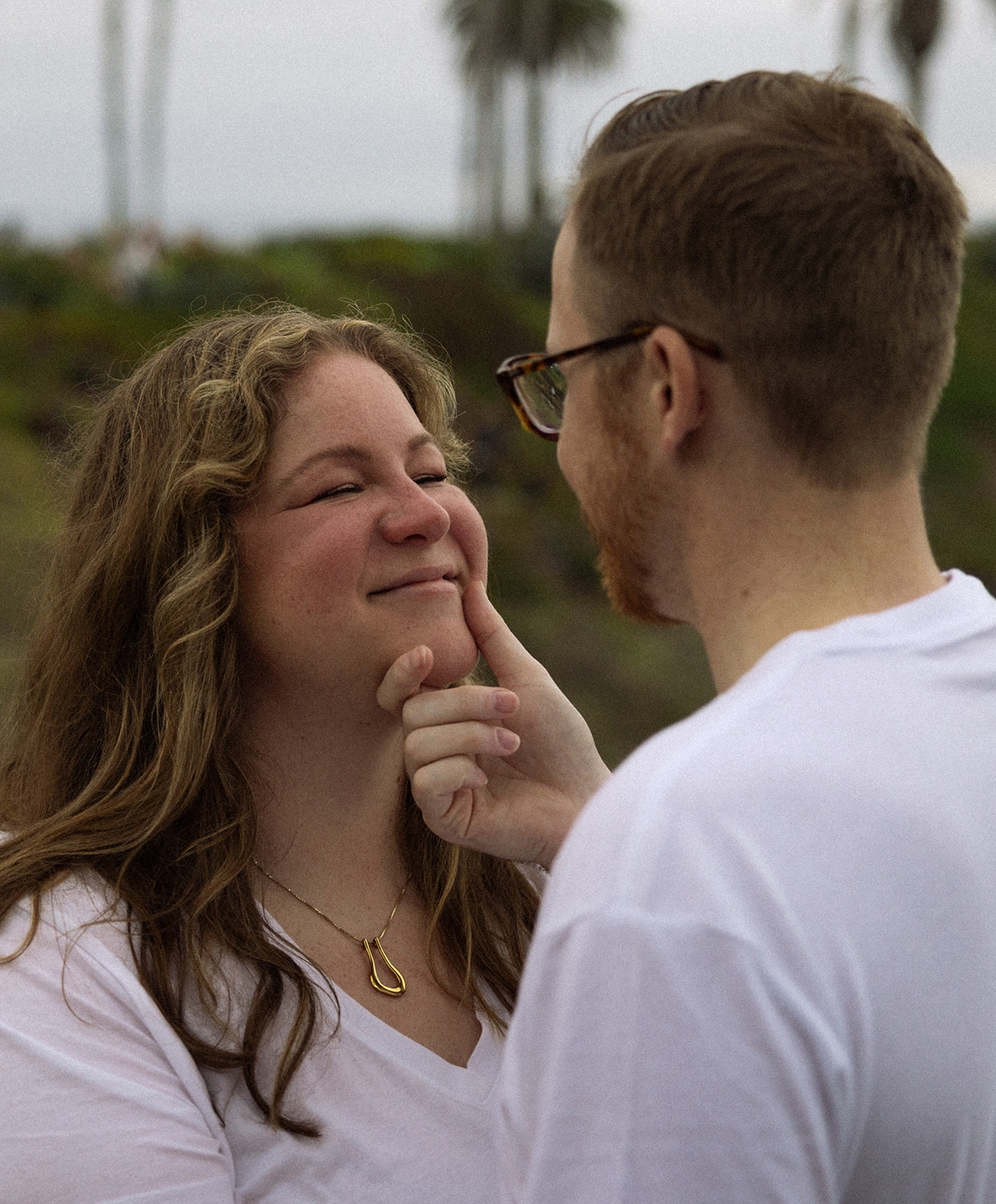 a man holding a woman's chin during beach engagement photos