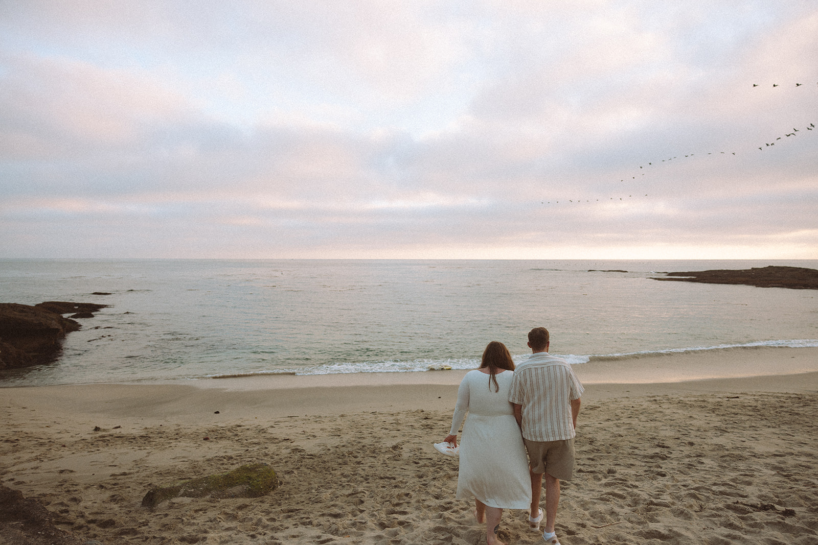 a couple walking onto the beach during their beach engagement photos in California