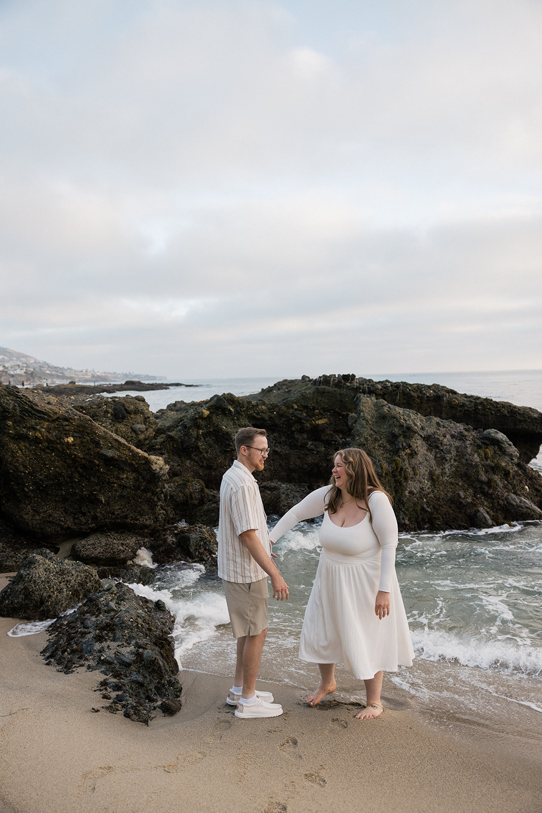 a couple playing on the beach together during their beach engagement photos in CA
