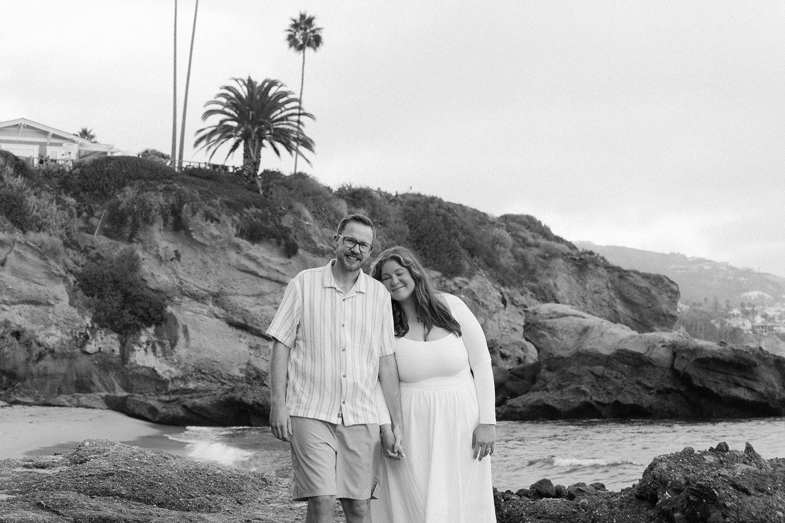 a couple holding hands as they smile on the beach 