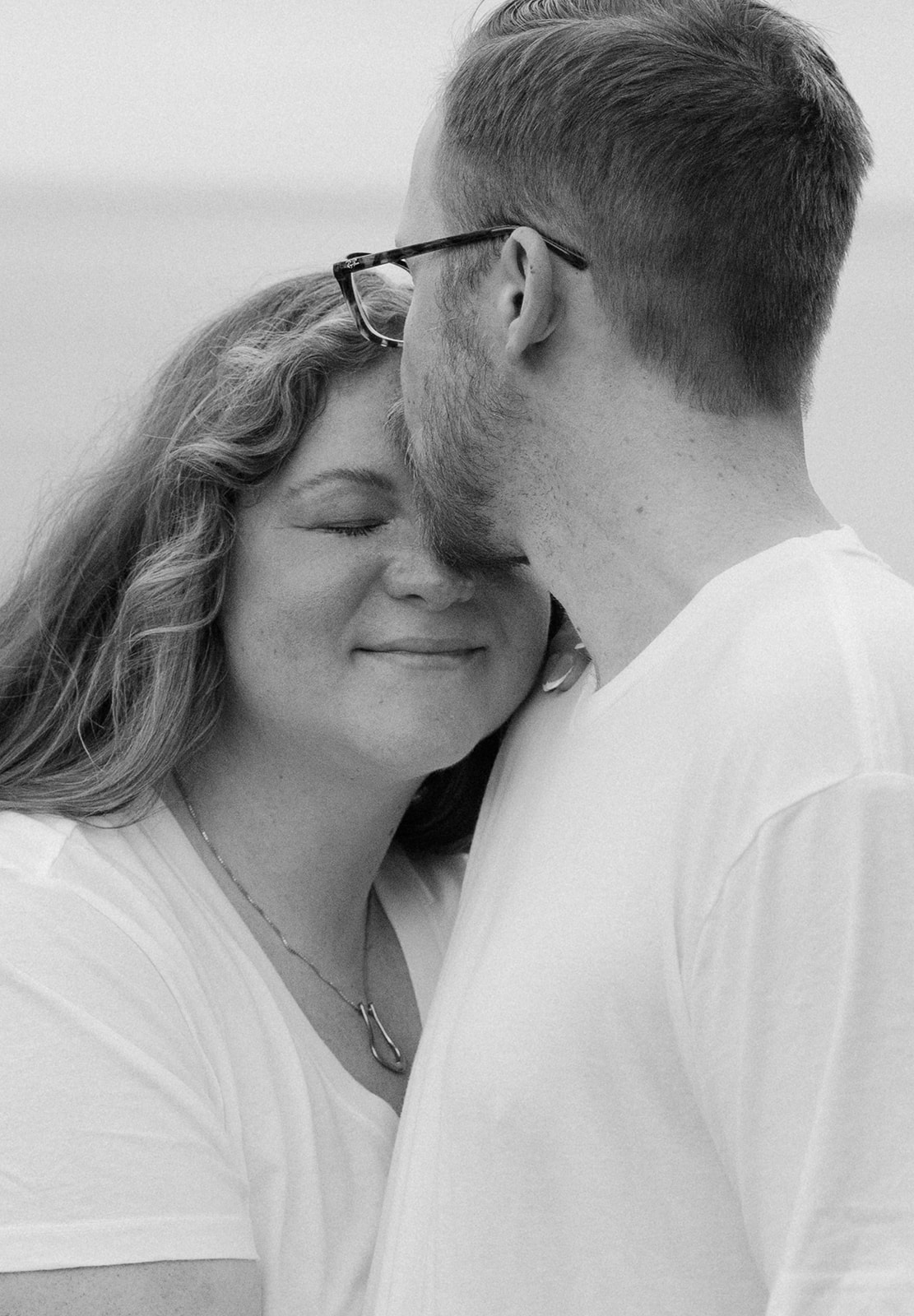 a man kissing a woman's forehead during their beach engagement photos in California 