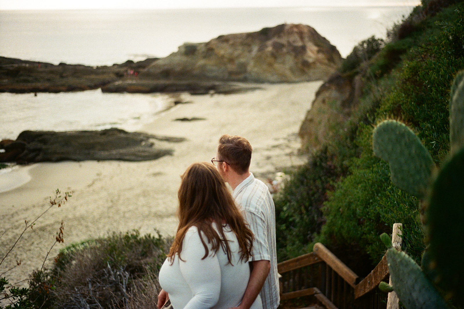 a couple looking out at the beach during their beach engagement photos
