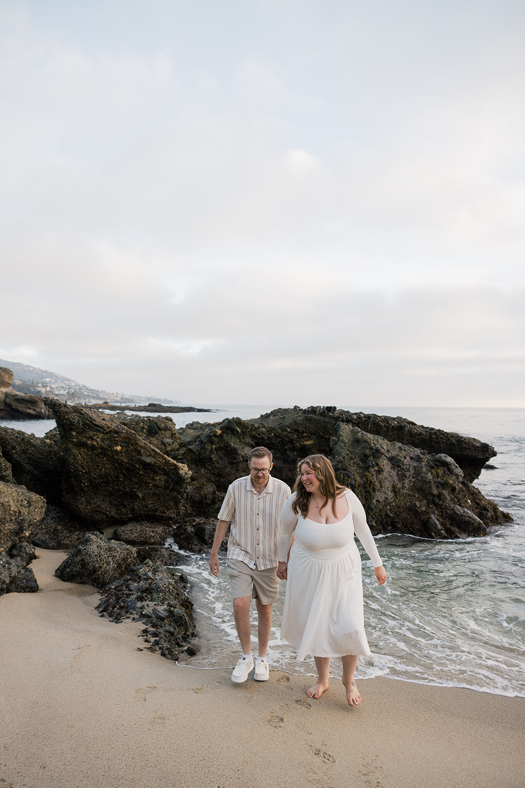 newly engaged couple walking on the beach together during their beach engagement photos